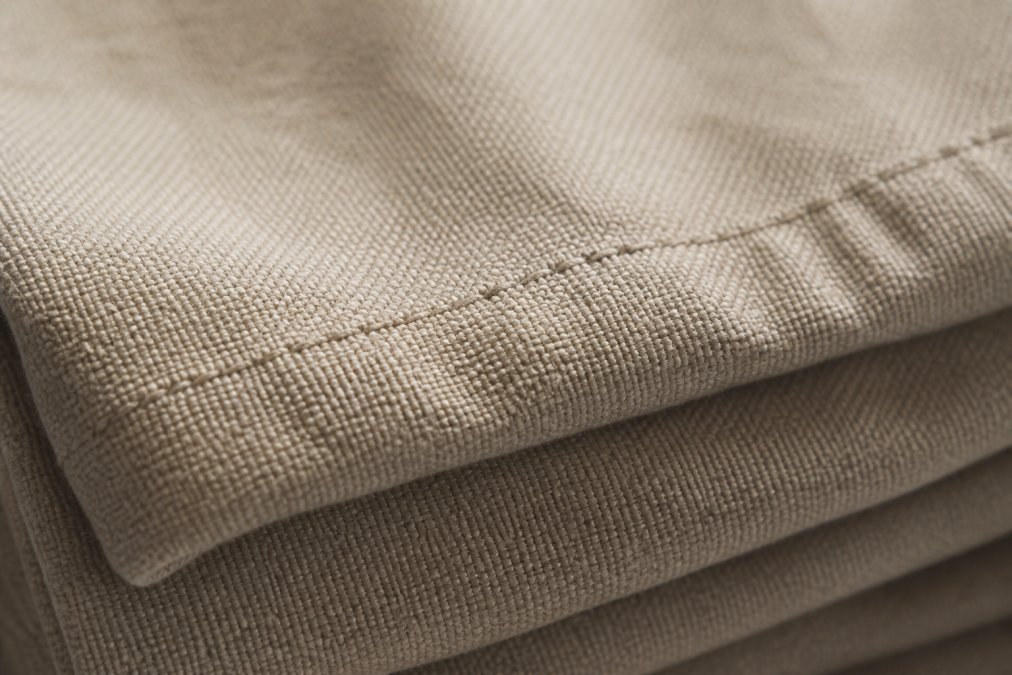 Close-up of heavyweight cotton fabric showing dense, tightly woven texture with visible stitch detail and premium hand-feel under natural lighting