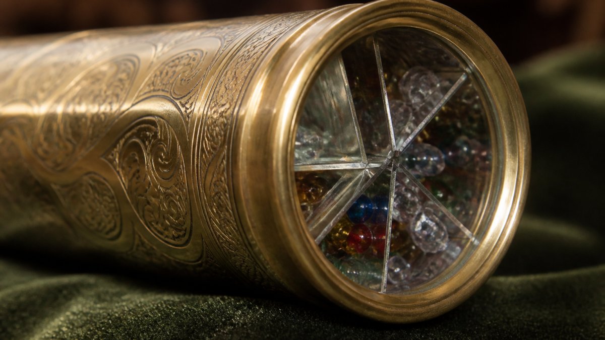 Close-up of intricate brass kaleidoscope barrel showing precision-etched details and polished mirror system visible through the glass viewing chamber, demonstrating handcrafted optical engineering