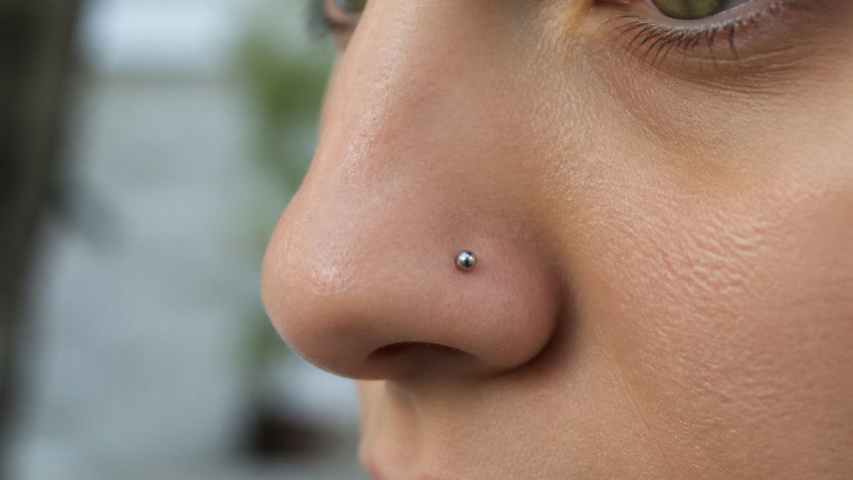 Diagram illustrating the biocompatibility benefits of titanium versus other metals for sensitive nose piercings