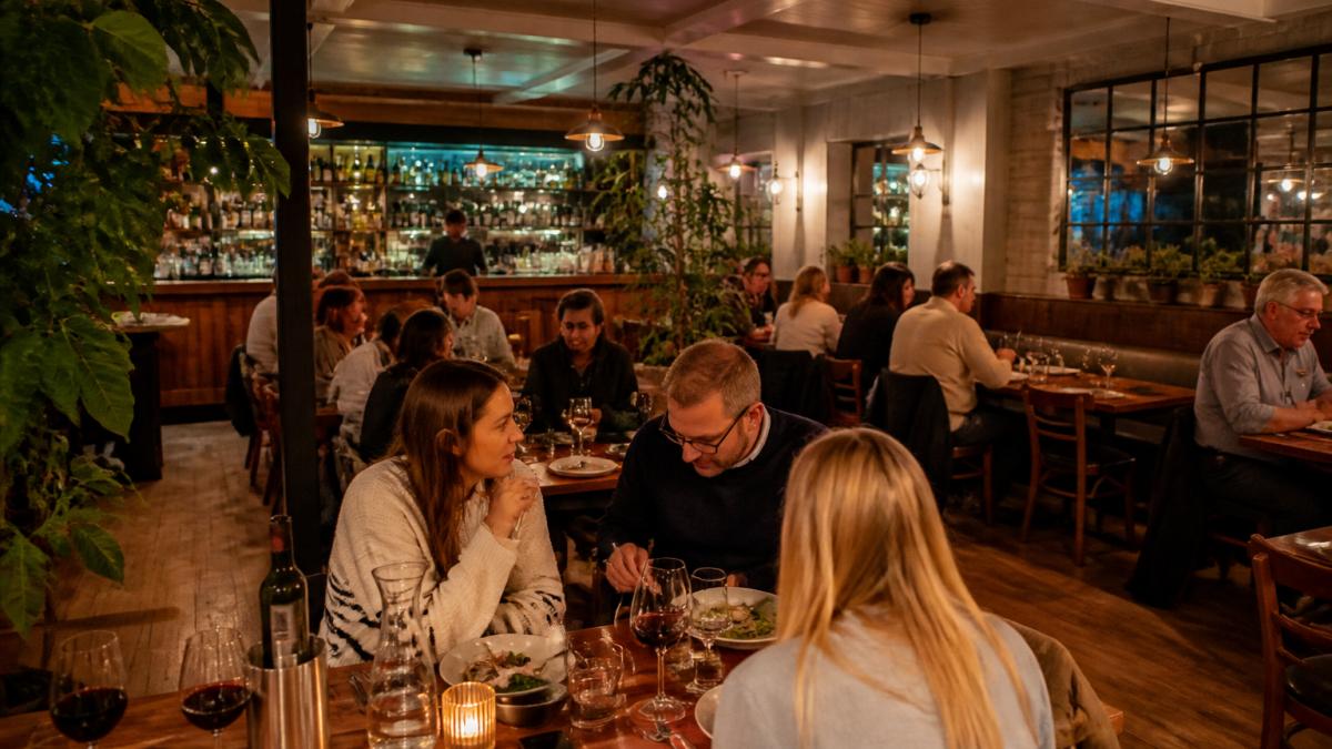 A warm, inviting independent restaurant interior in a British town, with wooden tables, soft lighting, and diners enjoying meals together in a relaxed atmosphere