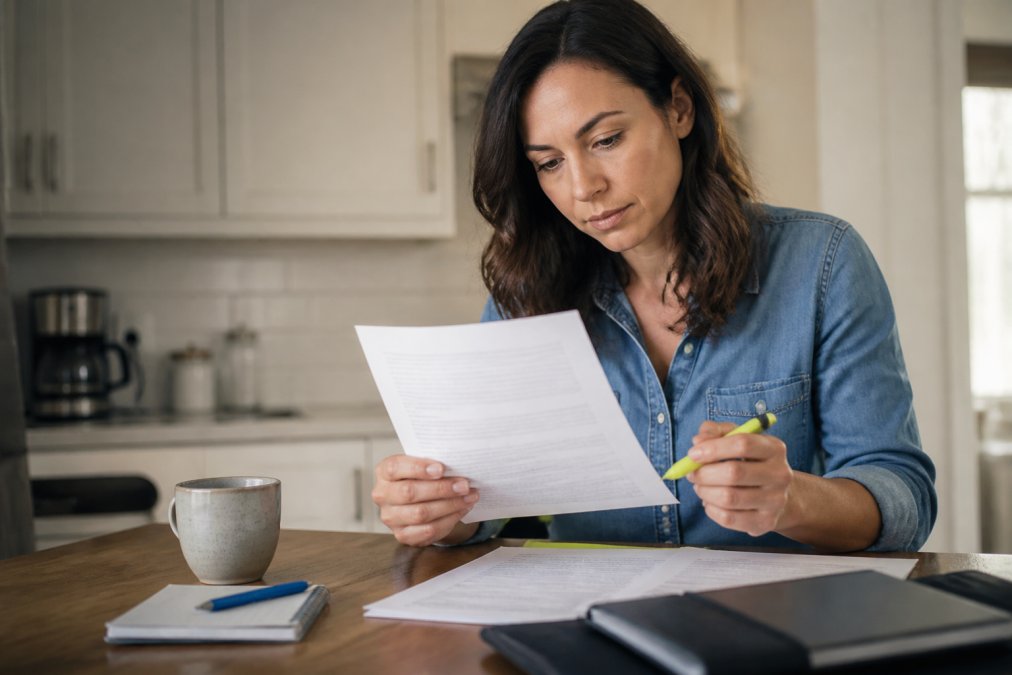 Woman reading an insurance policy with a highlighter to identify no hidden fees in the contract terms