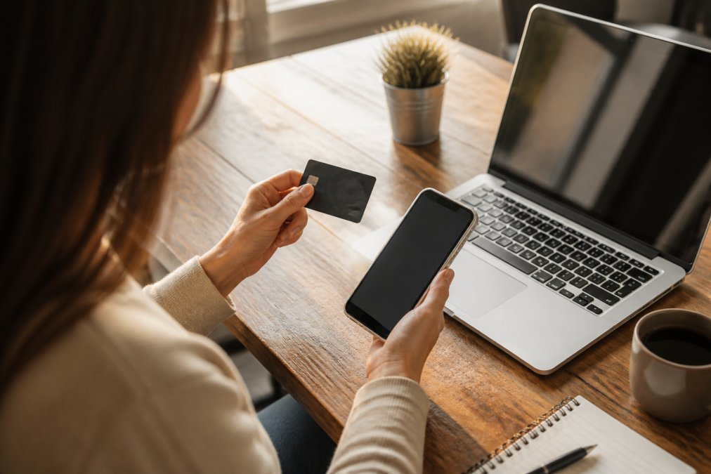 Person using a smartphone to select an interest free payment plan at an online checkout on a wooden desk