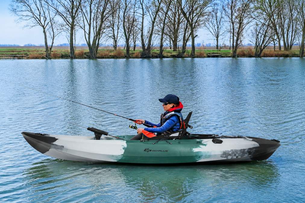 Beginner paddler sitting upright in a stable sit-on-top kayak on calm blue water, showing the wide flat hull design and comfortable open deck, with gentle ripples around the boat