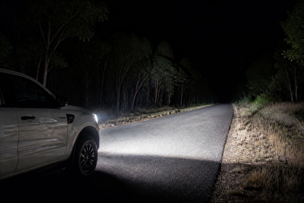 Ford Ranger with bright LED headlight kits casting a sharp beam on a dark rural road at night