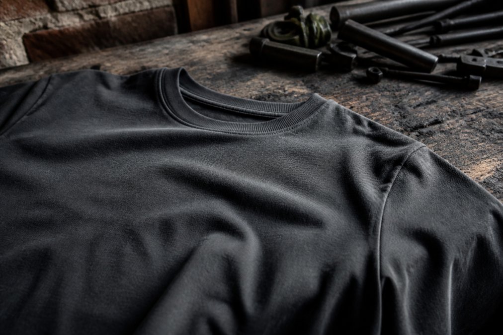 Close-up of heavyweight cotton fabric detailing the construction of long lasting streetwear on a wooden workbench.