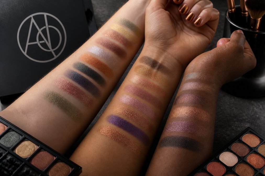 Close-up of richly pigmented eyeshadow swatches displayed on diverse skin tones, showing vibrant color intensity and seamless blendability under natural studio lighting