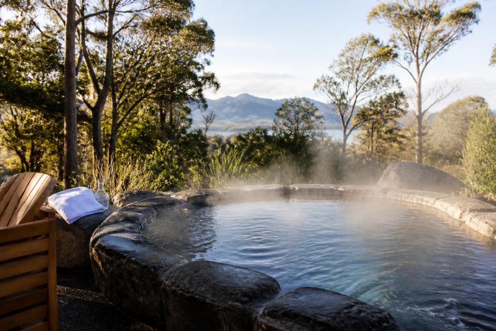 Serene thermal pool surrounded by natural Tasmanian landscape with steam rising gently, showcasing the peaceful sanctuary setting designed for executive retreat and rejuvenation