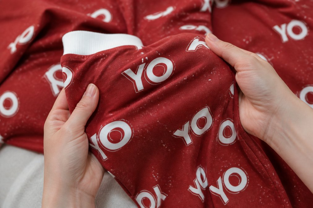 Close-up of soft cotton-spandex fabric texture being held in hands, showing the weave and drape of high-quality loungewear material with natural lighting
