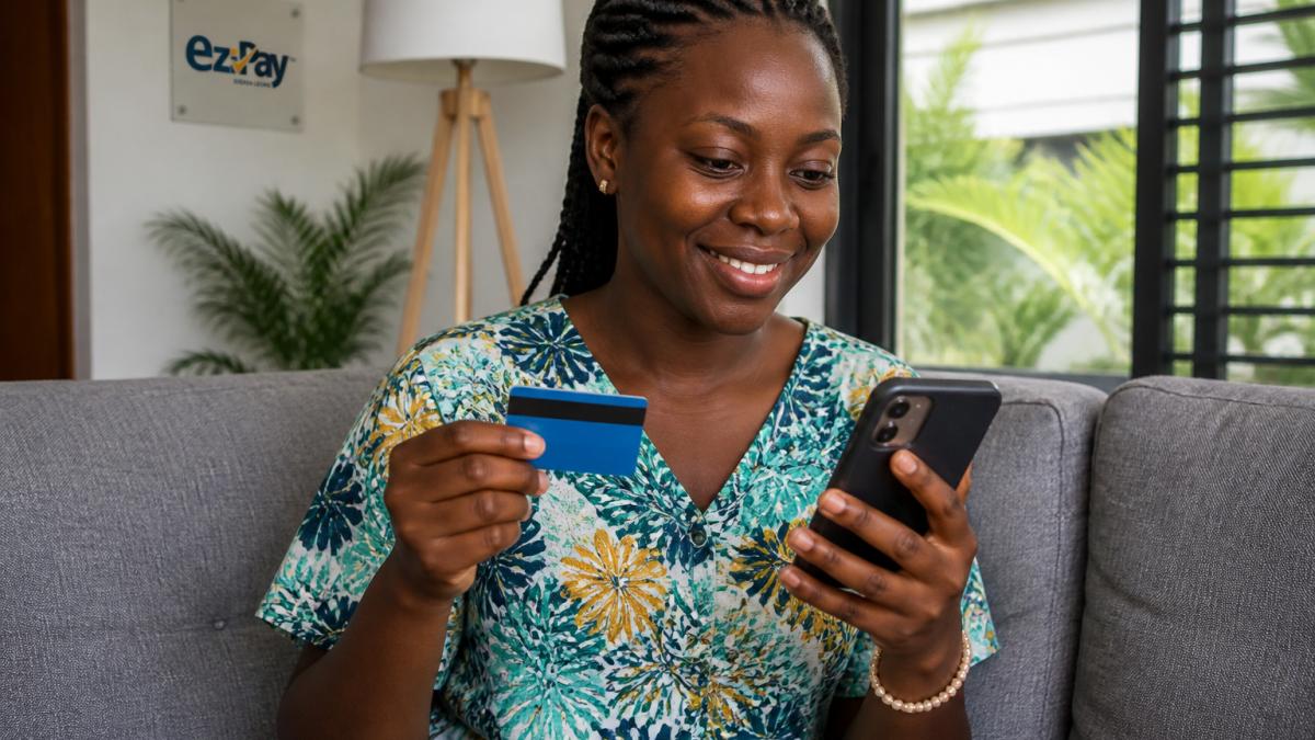 Person holding a smartphone with mobile money app interface visible, making a digital payment in a home setting with natural lighting