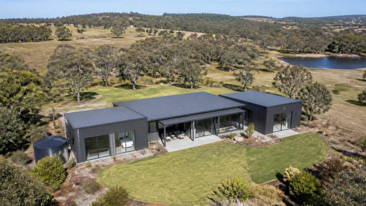Aerial view of completed steel-framed modular home on expansive rural property with open grassland and natural bushland surroundings