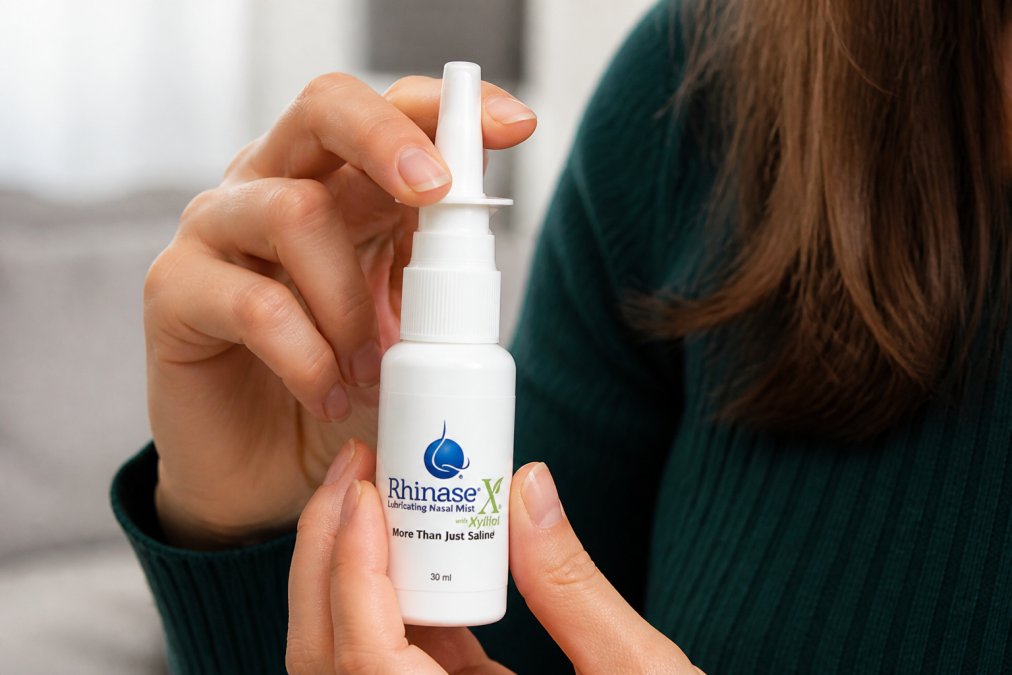 Close-up of hands holding a nasal spray bottle with clear labeling visible, showing the metered-dose applicator and proper grip in natural lighting