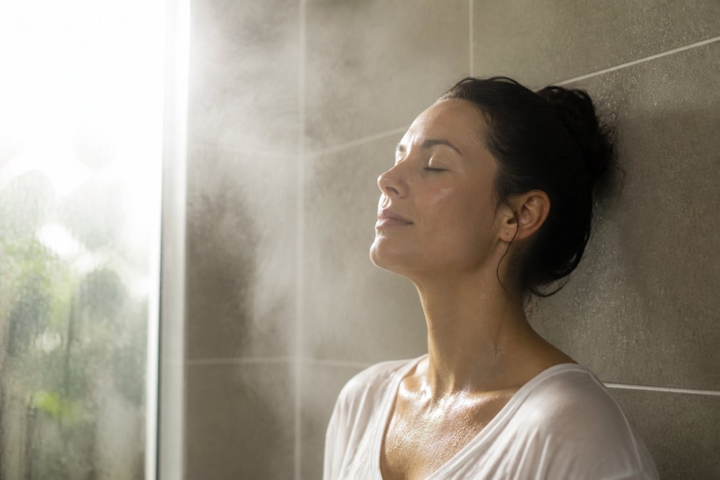 Person in steamy bathroom environment demonstrating natural humidity exposure for nasal health, with visible moisture in air and relaxed expression