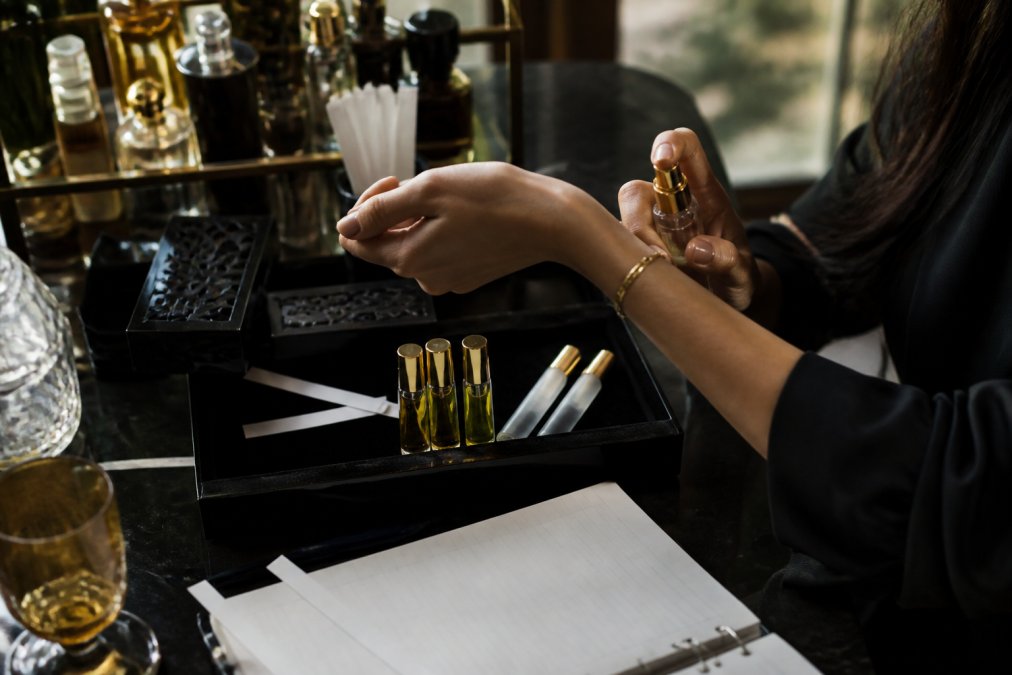 Person testing a scent from niche perfume discovery sets on their wrist using a small glass atomizer vial