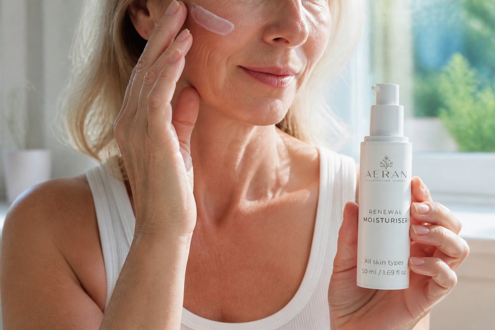 Hands holding a non-comedogenic moisturizer product demonstrating application on mature skin with visible fine lines, natural daylight illuminating the texture