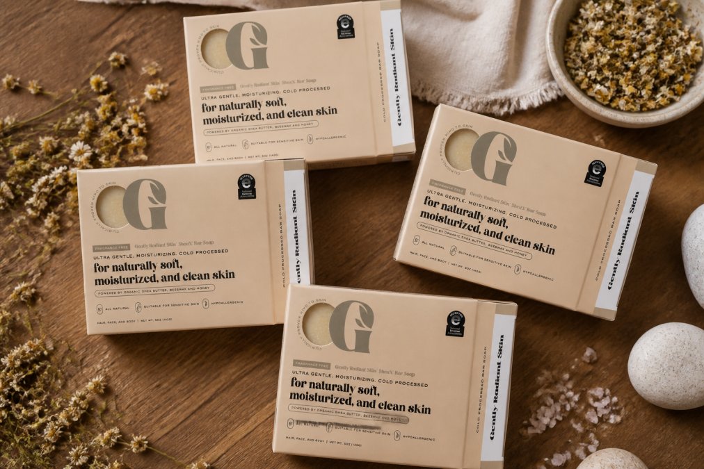 Flat lay of multiple SheaX bar soaps in different varieties arranged on a natural wooden surface with botanical elements like dried chamomile and sea salt, soft natural lighting
