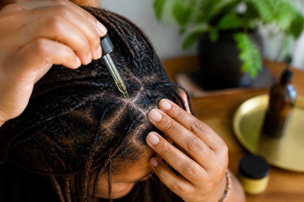 Person applying oil to their scalp to maintain loc hydration and health