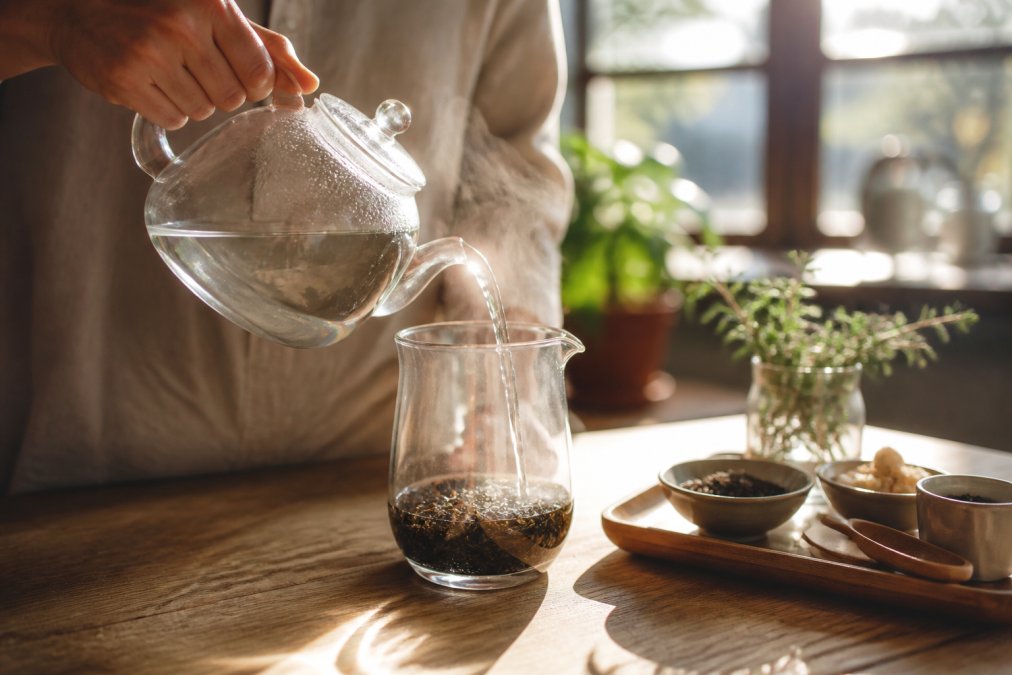 Hot water being poured over loose-leaf tea from top organic black tea brands into a glass brewing vessel