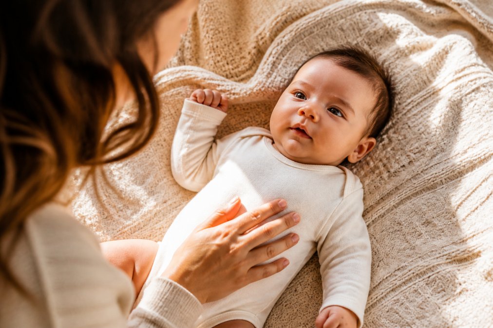 Baby wearing a soft organic cotton baby outfit while resting on a cozy knit blanket in warm sunlight.