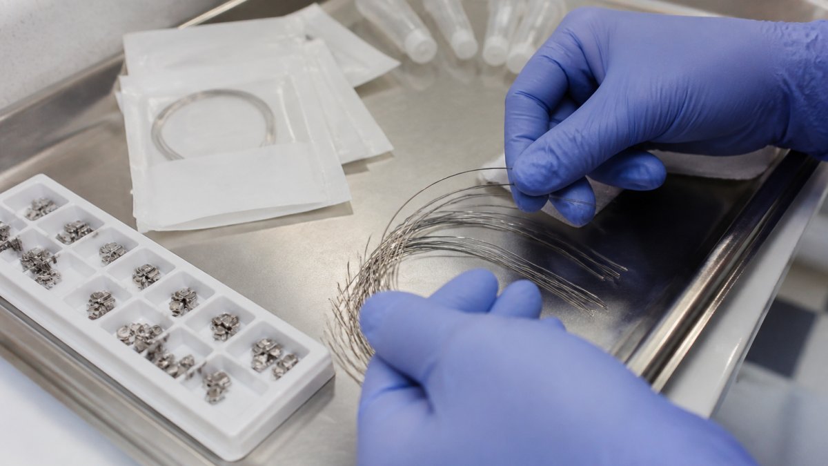 Gloved hands sorting stainless steel archwires from orthodontic wire manufacturers on a clinical tray