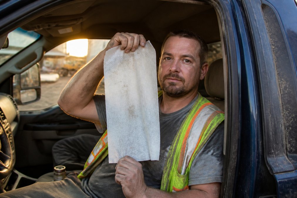 Construction worker holding oversized wipes to show scale in his truck