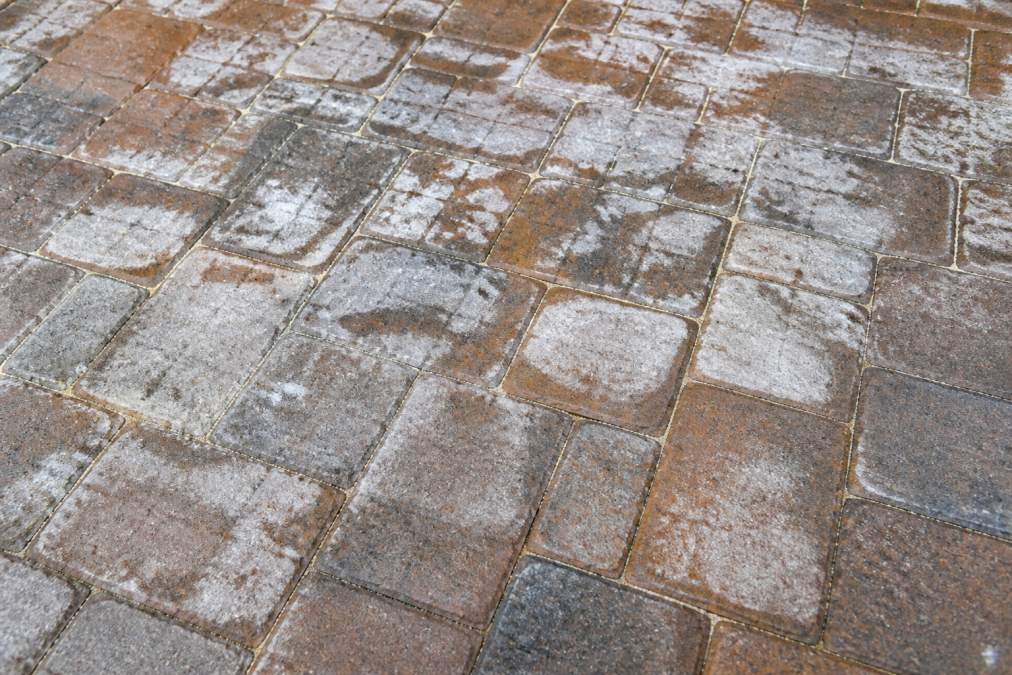 Close-up of paver surface showing white hazing and moisture marks from humidity exposure, with visible sealer deterioration and discolored areas