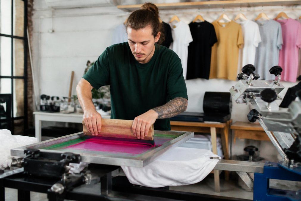 Step-by-step process of screen printing vibrant ink designs onto high-quality plain tees in a studio