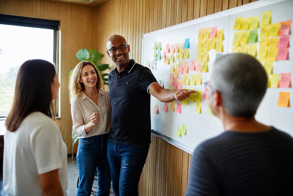 Diverse team collaborating on strategy with sticky notes to improve knowledge sharing in a modern office