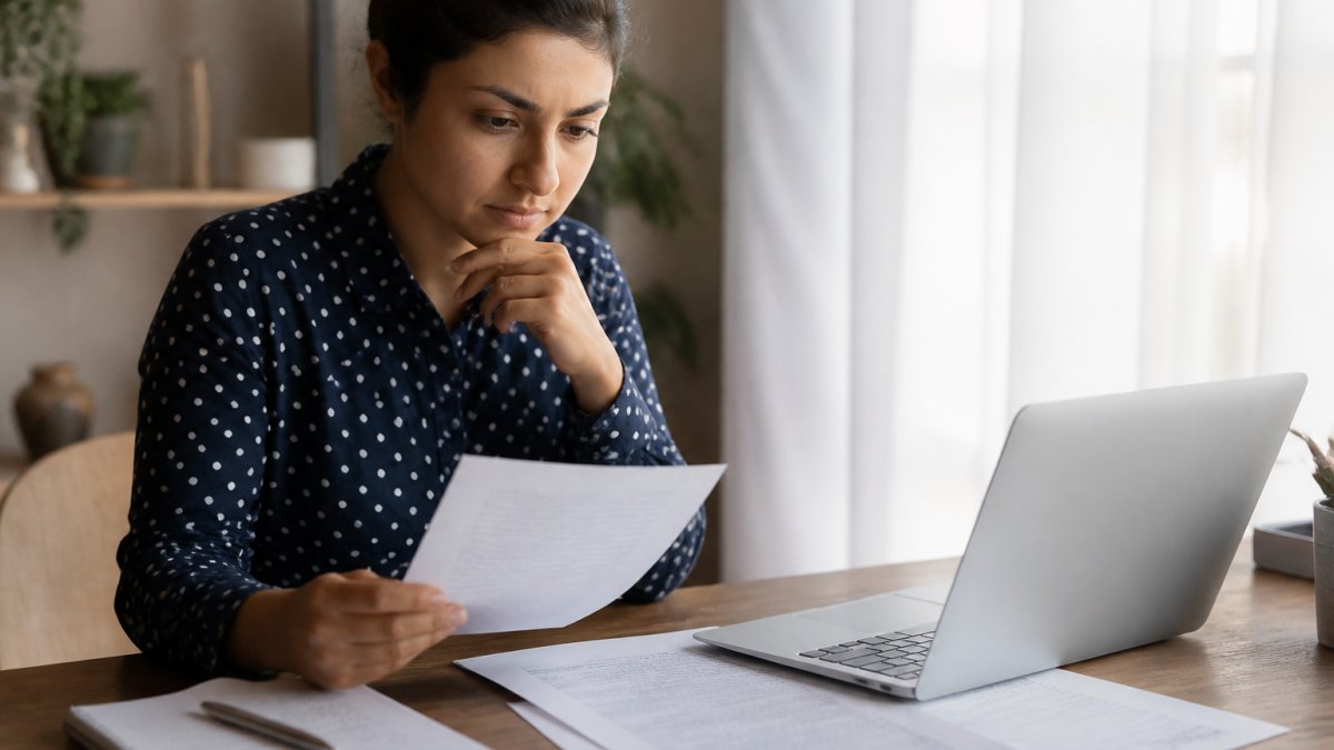 Person reviewing privacy settings on a laptop with documents and a notebook nearby, focused and attentive