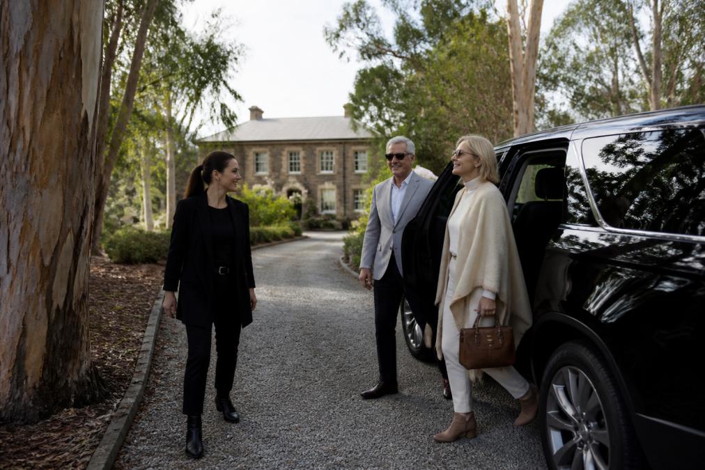 Travelers stepping out of a luxury SUV for private day tours at a heritage estate surrounded by eucalyptus trees.