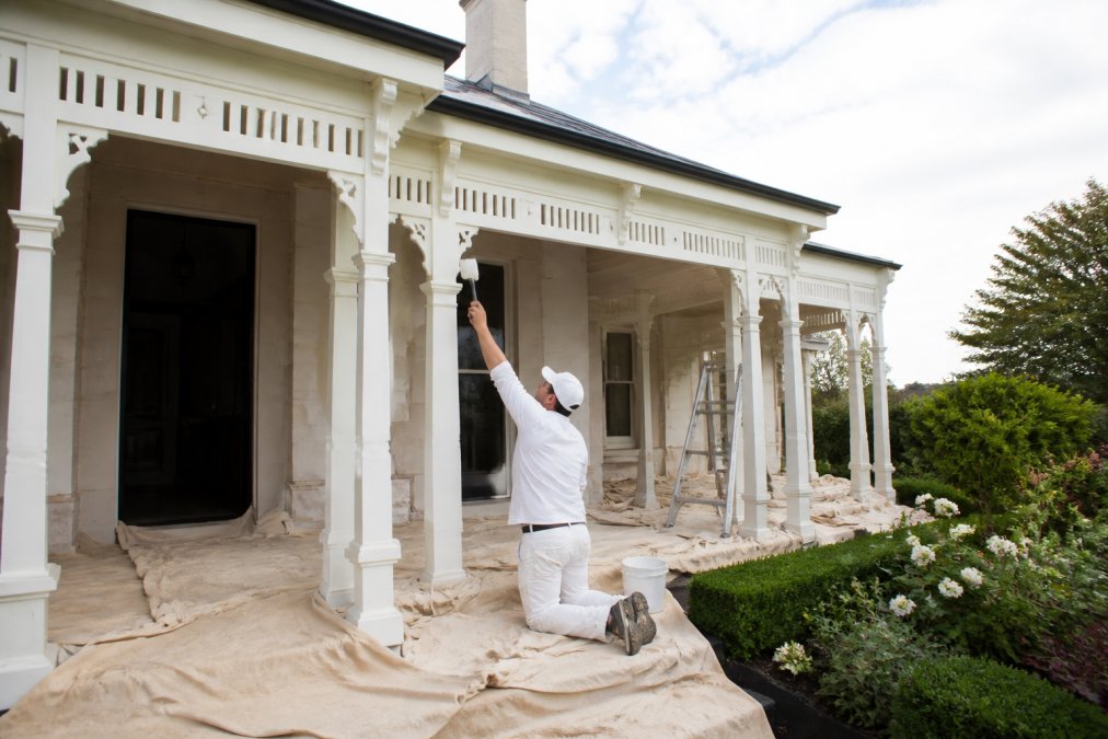 Professional painter providing meticulous painting services on the trim of a heritage home exterior.