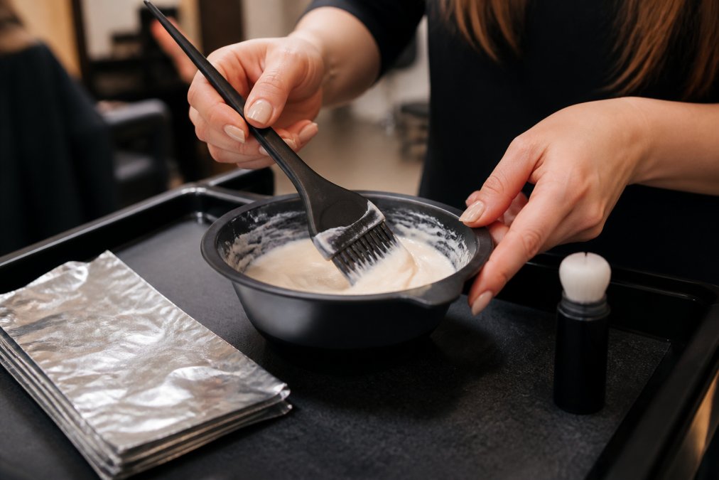 Professional colorist using tinting tools with a brush and bowl at a salon station