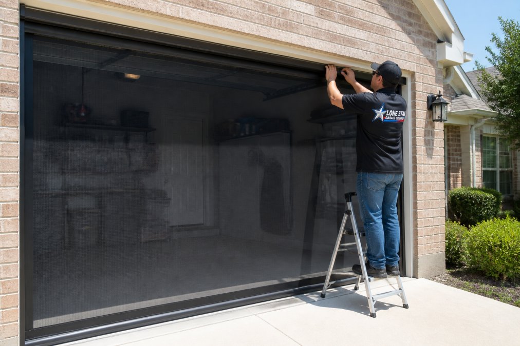 Professional installing retractable garage screen system on residential garage in bright Texas sunlight, showing the mesh fully extended and the sliding track system visible along the garage opening