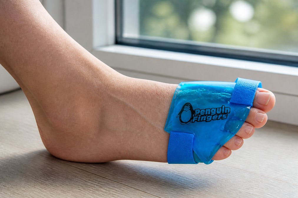 Close-up of a person's foot with a reusable gel cold wrap applied to the toes, showing proper positioning with the wrap snugly fitted around the forefoot and adjustable straps securing it in place, natural lighting from a window