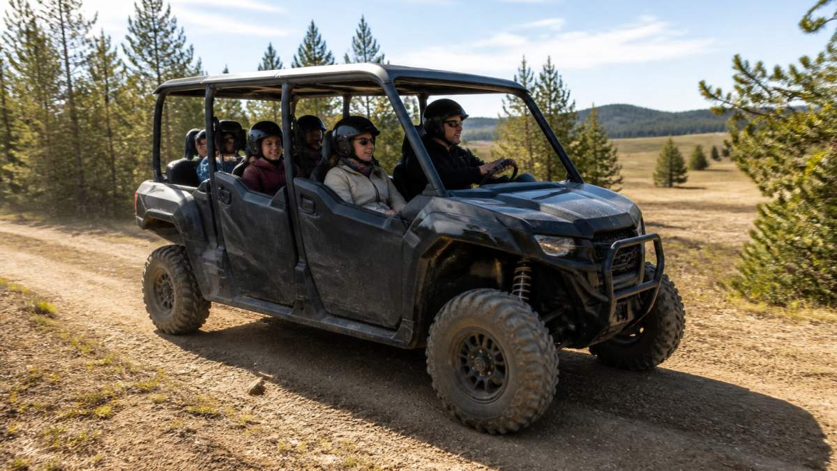 Family of five enjoying a recreational trail ride together in a side-by-side UTV on a sunny day with trees and open landscape in the background