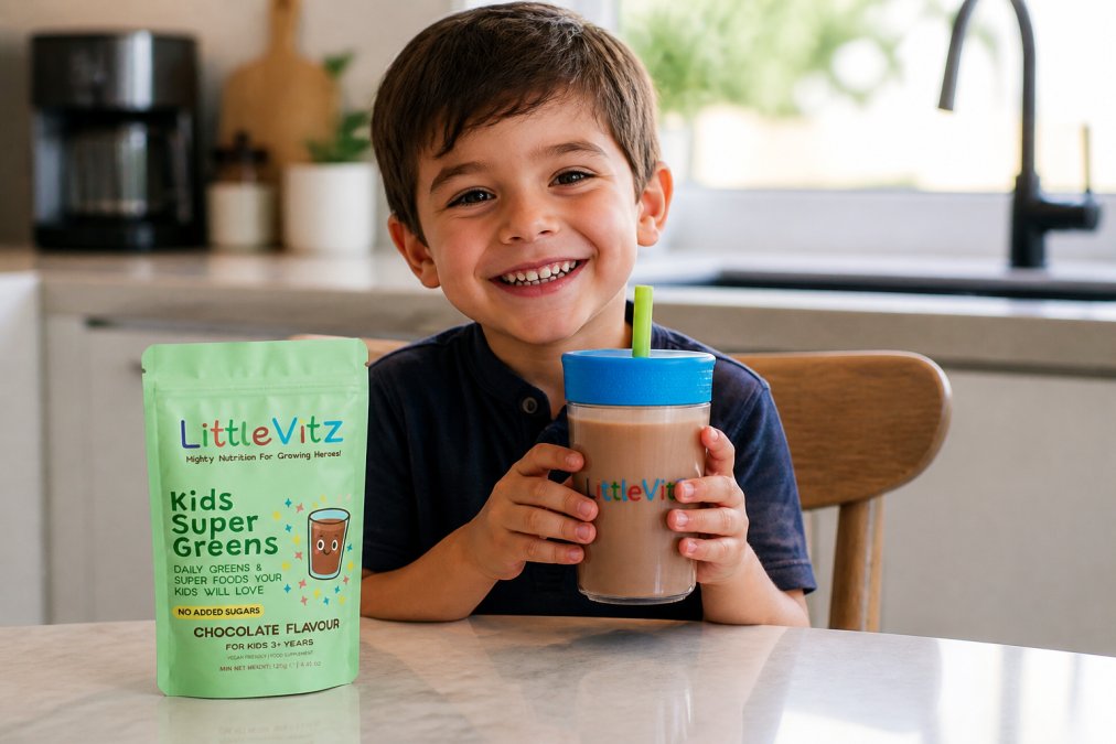 Young child happily holding a glass of rich chocolate-coloured milk or smoothie, beaming with genuine enthusiasm whilst seated at a bright kitchen table