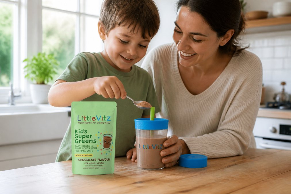 Parent and young child together in a bright, modern kitchen with natural sunlight streaming through windows, happily mixing chocolate powder into a tall glass of milk or blending a smoothie, both smiling and engaged
