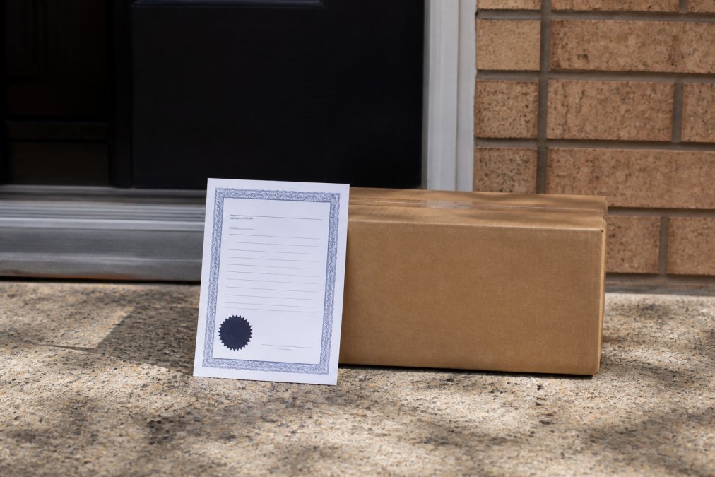 A delivery package being placed on a doorstep with a warranty document visible alongside it, showing the logistics and protection aspects of online auto parts purchasing