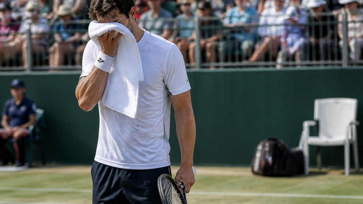 Competitive tennis player using tennis sports psychology exercises to reset composure at the baseline during a match.