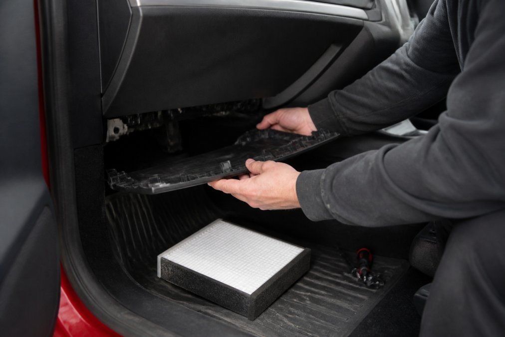 Technician removing the dashboard panel to access the Tesla Model 3 cabin air filter housing