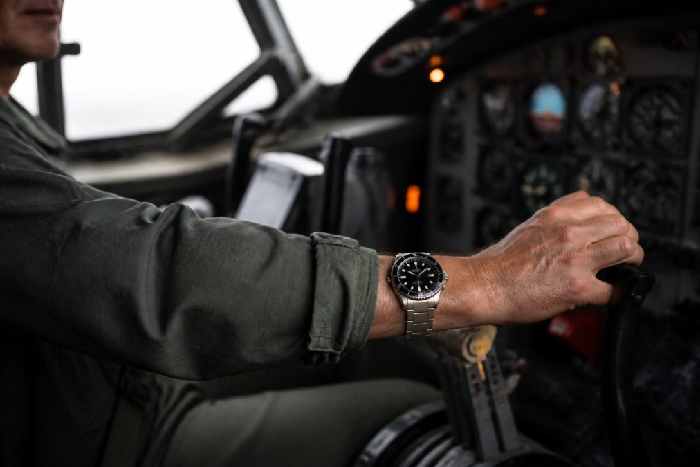 Professional pilot or technician wearing a titanium watch in a cockpit or technical workspace, demonstrating real-world durability with natural lighting showing the refined case and movement