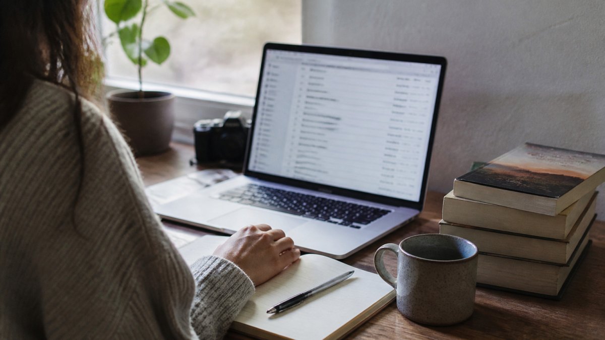 Indie author using email marketing tools at a wooden desk with coffee