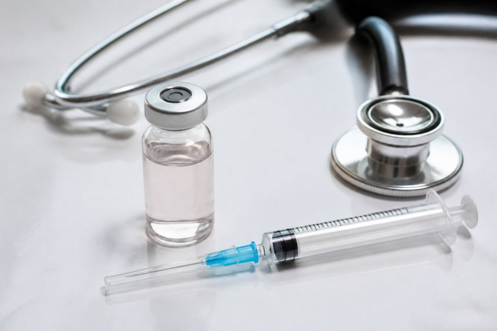 A clean clinical desk with a vial of methylcobalamin, a pre-filled syringe, and a stethoscope arranged under bright, even lighting