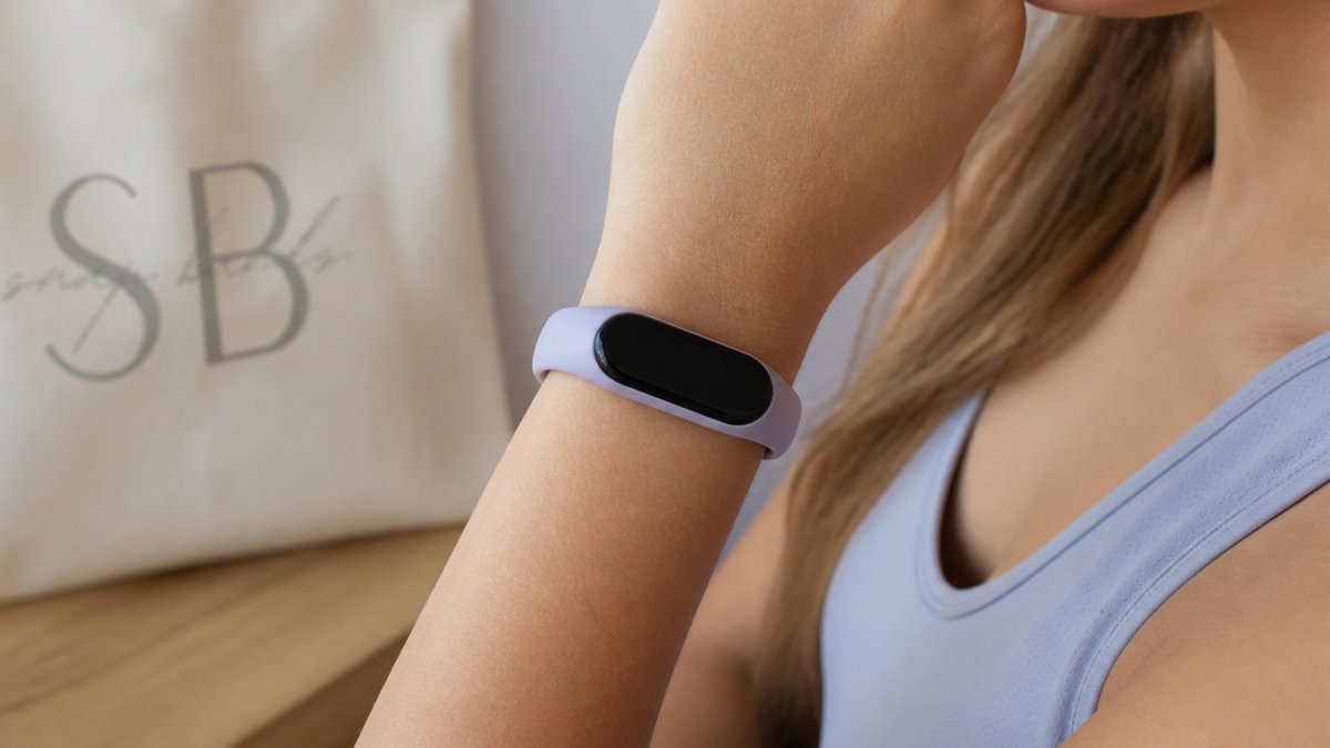 Close-up of a woman's wrist wearing a soft silicone fitness tracker band, showing a comfortable snug fit against the skin
