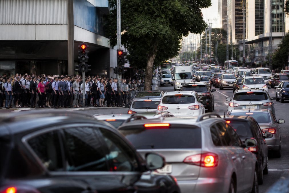 Busy Perth street intersection during morning rush hour with heavy traffic, crowds of commuters waiting at traffic lights, and multiple vehicles congested at intersection