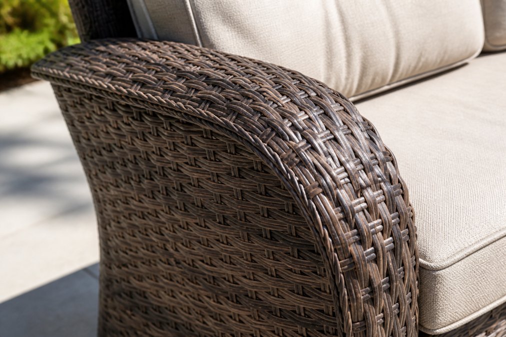 Close-up of hand-woven PE rattan wicker on an outdoor sofa, showing the intricate weave pattern and texture with natural sunlight highlighting the material's durability and color consistency