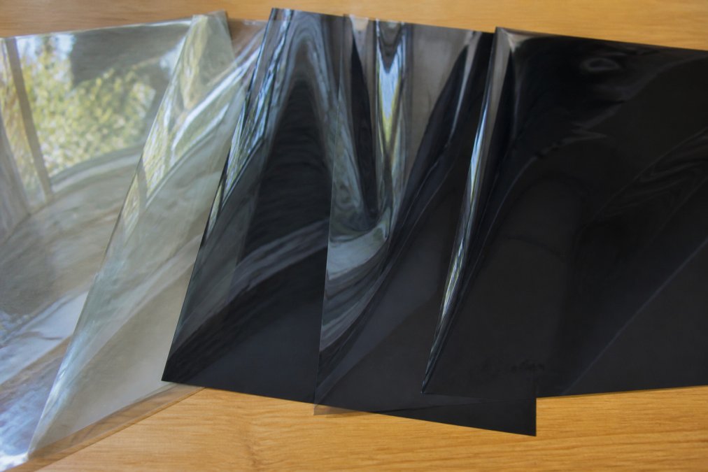 Close-up of different window film samples showing ceramic, metallic, and dyed film textures with natural light reflecting across each surface