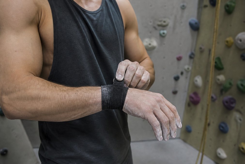 Climber adjusting the best wrist wrap for climbing before gripping a hold at an indoor gym