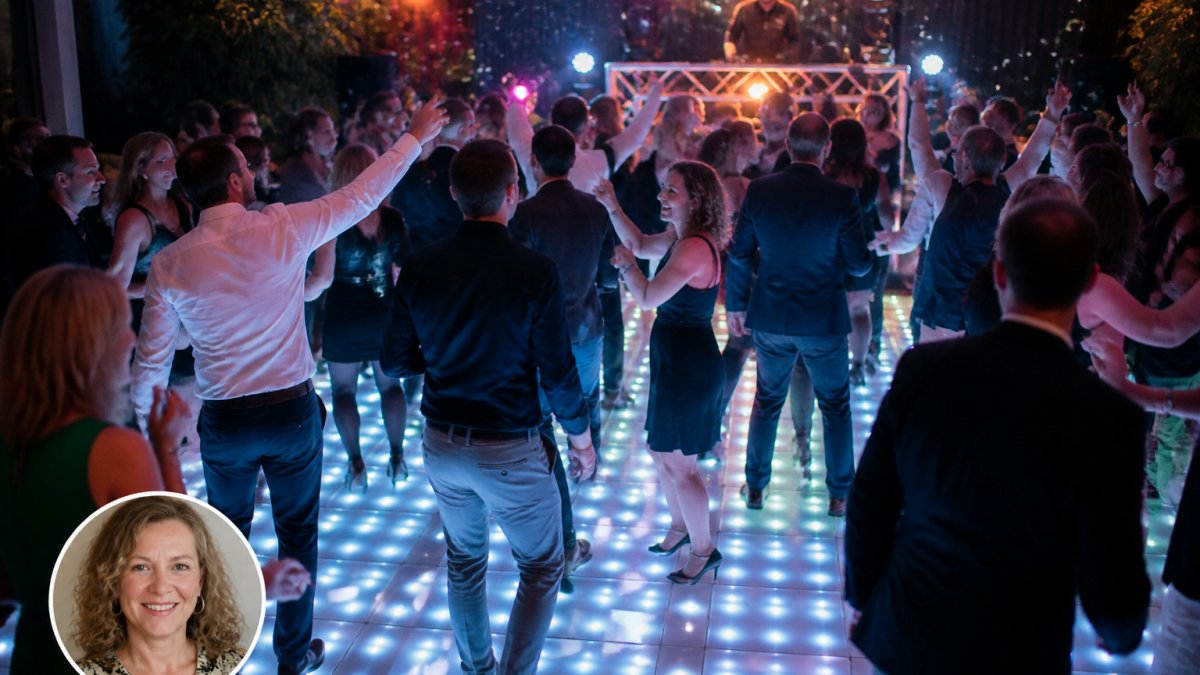 Feestende mensen op een verlichte dansvloer tijdens een bedrijfsfeest, met op de achtergrond sfeervolle verlichting en een DJ