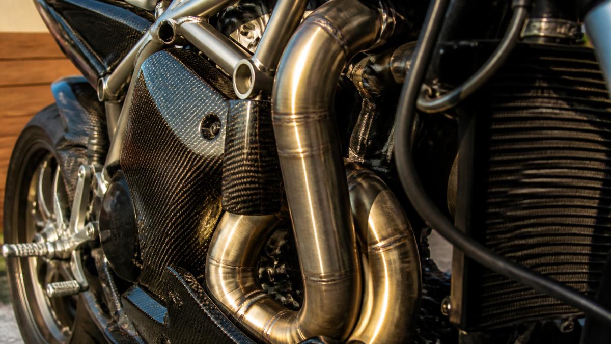 Close-up van titanium headers en carbon-kappen van de KTM Super Duke RR in showroomstaat, zonlicht op de details, nadruk op craftsmanship