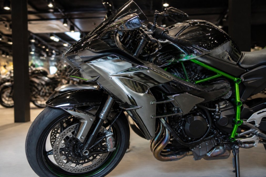 Close-up van de Kawasaki Ninja H2 in Black Chrome kleur, met focus op het futuristische design en supercharger details, zichtbaar in een showroom met professionele verlichting en reflectie op het glanzende oppervlak